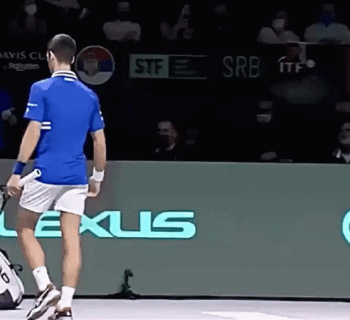 A Man In A Blue Shirt And White Shorts Is Holding A Tennis Racquet In Front Of A Lexus Sign . GIF
