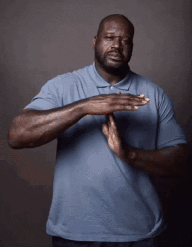 A Man In A Blue Shirt Holds His Hands Together In Front Of His Chest GIF