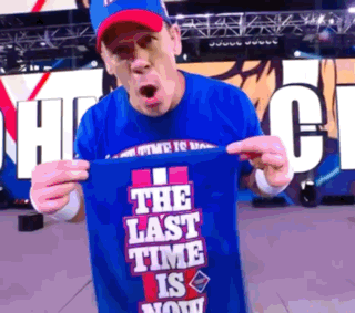 A Man In A Blue Shirt Holds Up A Shirt That Says The Last Time Is Now GIF