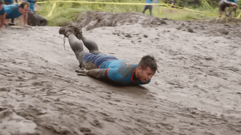 A Man In A Blue Shirt Is Crawling In The Mud . GIF
