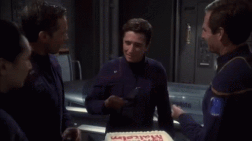 A Man In A Blue Shirt Is Cutting A Cake That Says Happy Birthday GIF