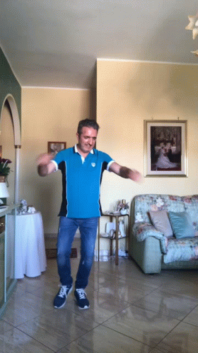A Man In A Blue Shirt Is Dancing In Front Of A Picture Of A Bride And Groom GIF