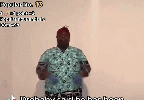 A Man In A Blue Shirt Is Dancing In Front Of A White Wall With The Words Popular No. 13 Above Him GIF