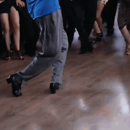 A Man In A Blue Shirt Is Dancing With A Group Of People GIF