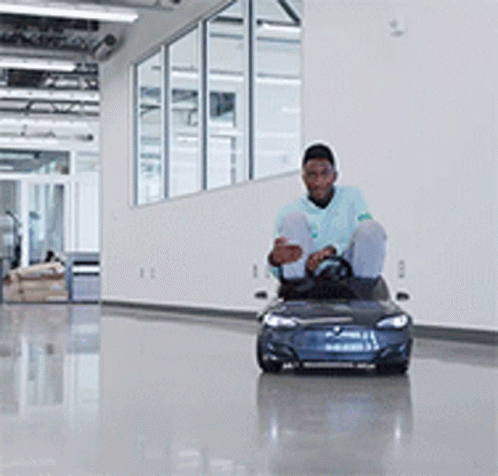 A Man In A Blue Shirt Is Driving A Blue Toy Car GIF