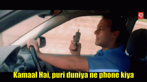 A Man In A Blue Shirt Is Driving A Car While Holding A Cell Phone GIF