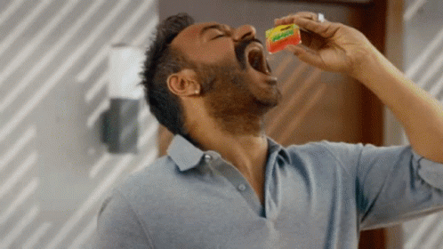A Man In A Blue Shirt Is Eating A Packet Of Gummy Bears GIF