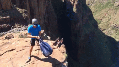 A Man In A Blue Shirt Is Holding A Bag That Says Alpina GIF