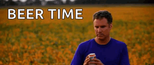 a man in a blue shirt is holding a can of beer in a field .