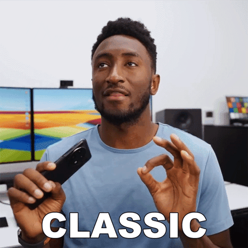 A Man In A Blue Shirt Is Holding A Cell Phone And The Word Classic Is On The Screen GIF