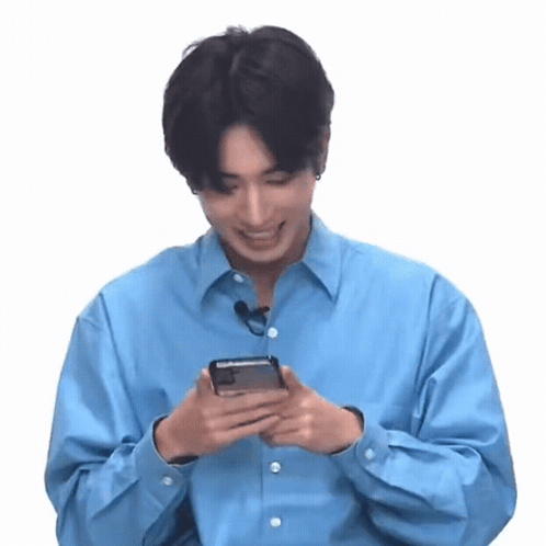 A Man In A Blue Shirt Is Holding A Cell Phone In His Hands . GIF