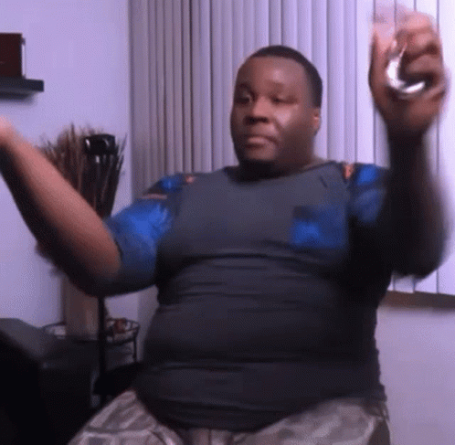 A Man In A Blue Shirt Is Holding A Glass In His Right Hand GIF