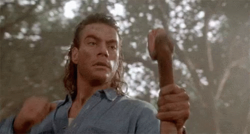 A Man In A Blue Shirt Is Holding A Hammer In His Hand . GIF