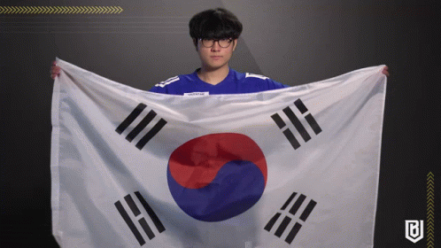 A Man In A Blue Shirt Is Holding A Korean Flag In His Hands GIF