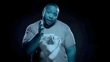 A Man In A Blue Shirt Is Holding A Pair Of Scissors In His Hands . GIF