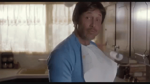 A Man In A Blue Shirt Is Holding A Piece Of Paper In His Mouth . GIF