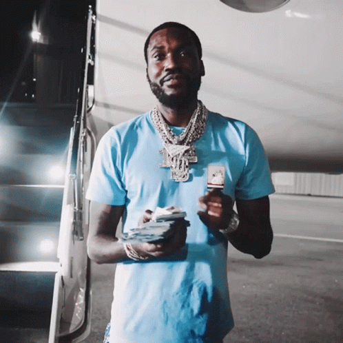 A Man In A Blue Shirt Is Holding A Pile Of Money GIF
