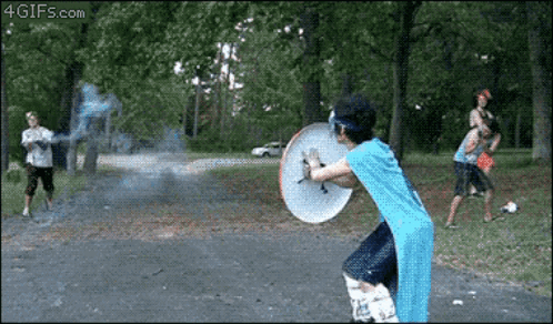 A Man In A Blue Shirt Is Holding A Shield While Playing Frisbee GIF