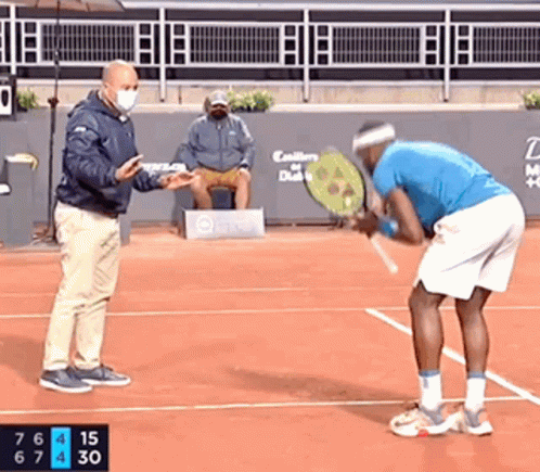 a man in a blue shirt is holding a tennis racquet on a tennis court