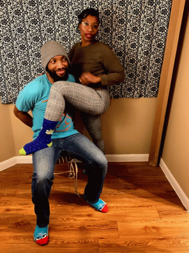 A Man In A Blue Shirt Is Holding A Woman 'S Legs GIF