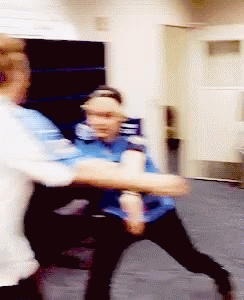 A Man In A Blue Shirt Is Holding Another Man 'S Arm GIF