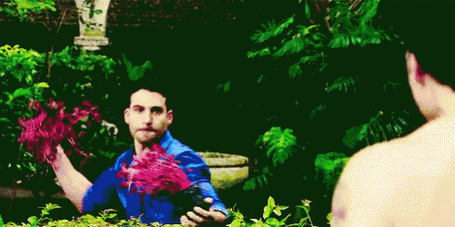 A Man In A Blue Shirt Is Holding Flowers In His Hands GIF