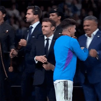 A Man In A Blue Shirt Is Hugging A Man In A Suit . GIF