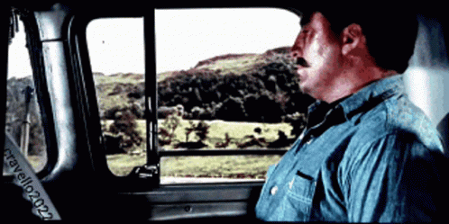 A Man In A Blue Shirt Is Looking Out A Window With A Watermark That Says ' California 2021 ' GIF