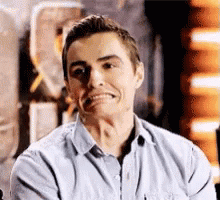 A Man In A Blue Shirt Is Making A Funny Face While Sitting Down . GIF