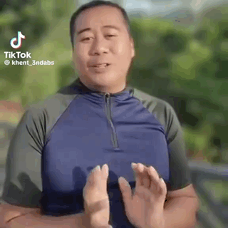 A Man In A Blue Shirt Is Making A Funny Face With His Hands In Front Of His Face . GIF
