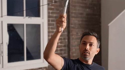 A Man In A Blue Shirt Is Measuring Something GIF