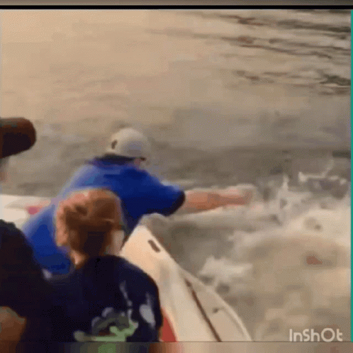 A Man In A Blue Shirt Is Riding A Boat In The Ocean . GIF