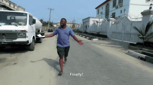 A Man In A Blue Shirt Is Running Down A Street With The Words Finally Written Below Him GIF