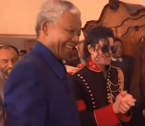 A Man In A Blue Shirt Is Shaking Hands With A Man In A Military Uniform . GIF