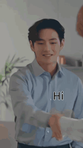 A Man In A Blue Shirt Is Shaking Hands With Another Man In A Kitchen While Smiling . GIF