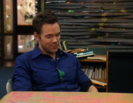 a man in a blue shirt is sitting at a table in front of a stack of books