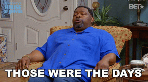 A Man In A Blue Shirt Is Sitting In A Chair With The Words " Those Were The Days " Above Him GIF
