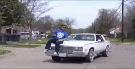 A Man In A Blue Shirt Is Sitting In A White Car GIF