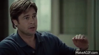 A Man In A Blue Shirt Is Sitting In Front Of A Window Talking To Someone . GIF