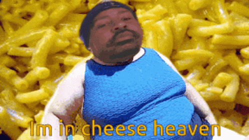 A Man In A Blue Shirt Is Sitting In Front Of Macaroni And Cheese GIF
