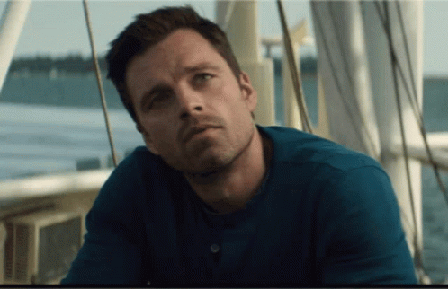 A Man In A Blue Shirt Is Sitting On A Boat Near The Water GIF