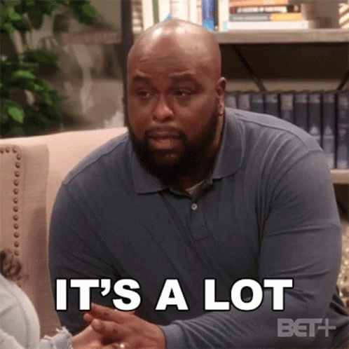 A Man In A Blue Shirt Is Sitting On A Couch And Talking To Another Man . GIF