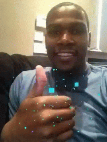 A Man In A Blue Shirt Is Smiling And Holding A Glass In His Hand GIF