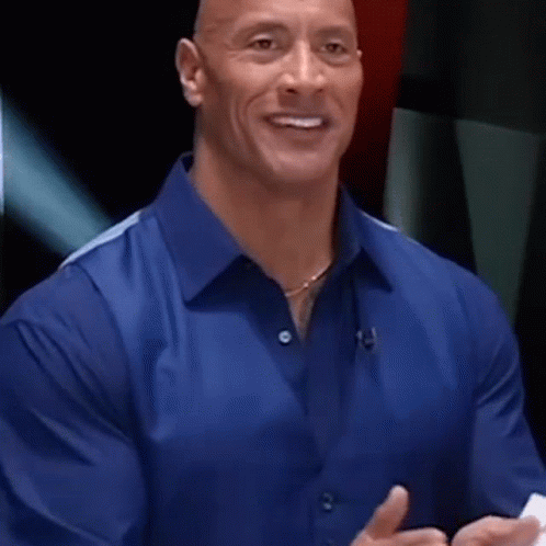 A Man In A Blue Shirt Is Smiling And Talking While Holding A Piece Of Paper . GIF