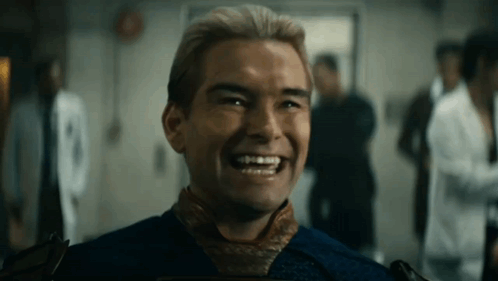 A Man In A Blue Shirt Is Smiling In A Room With Other People . GIF