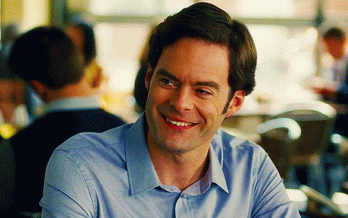 A Man In A Blue Shirt Is Smiling In Front Of A Crowd GIF