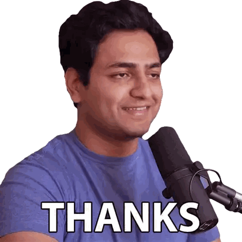a man in a blue shirt is smiling in front of a microphone with the words thanks written on his chest