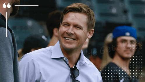 A Man In A Blue Shirt Is Smiling In Front Of A Quote GIF