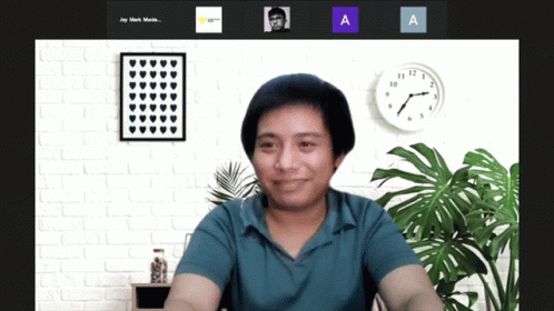 A Man In A Blue Shirt Is Smiling In Front Of A Wall With A Clock That Says 10:08 GIF