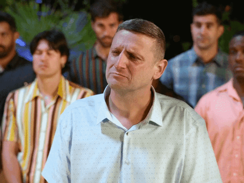 A Man In A Blue Shirt Is Standing In A Crowd Of Men GIF
